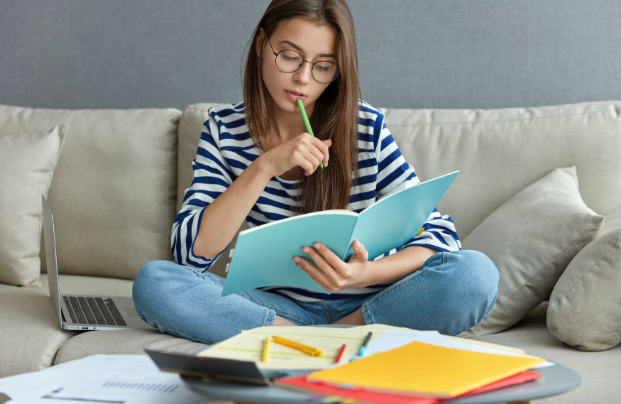 student showing how learning works through focused reading and note review at home