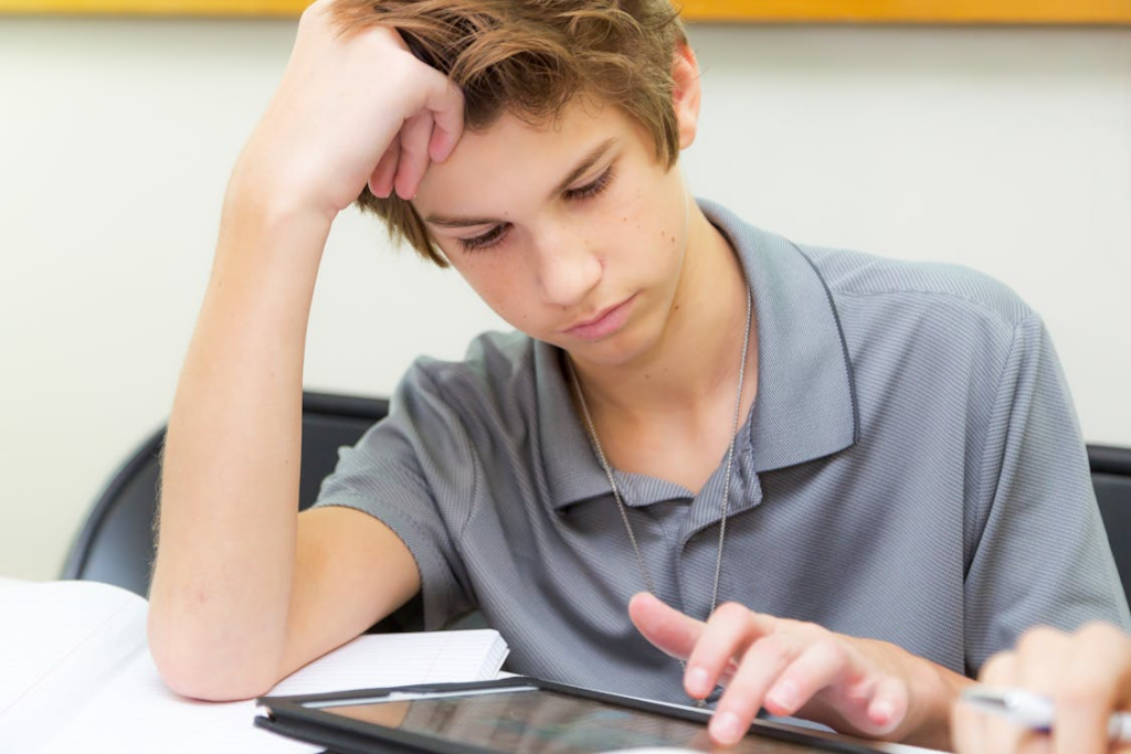 student trying to study with no motivation while looking tired and distracted at a desk