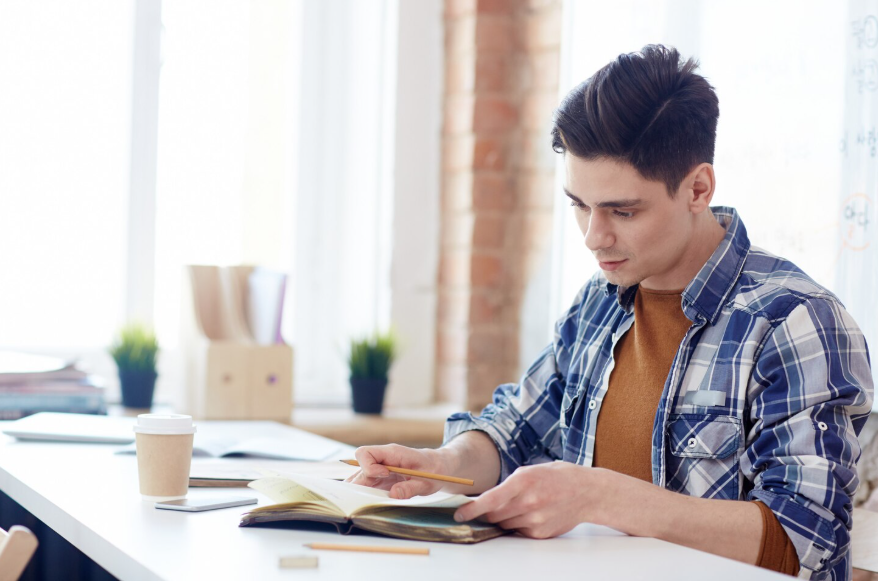 student using how to review before a test strategies while reading and taking notes at a desk