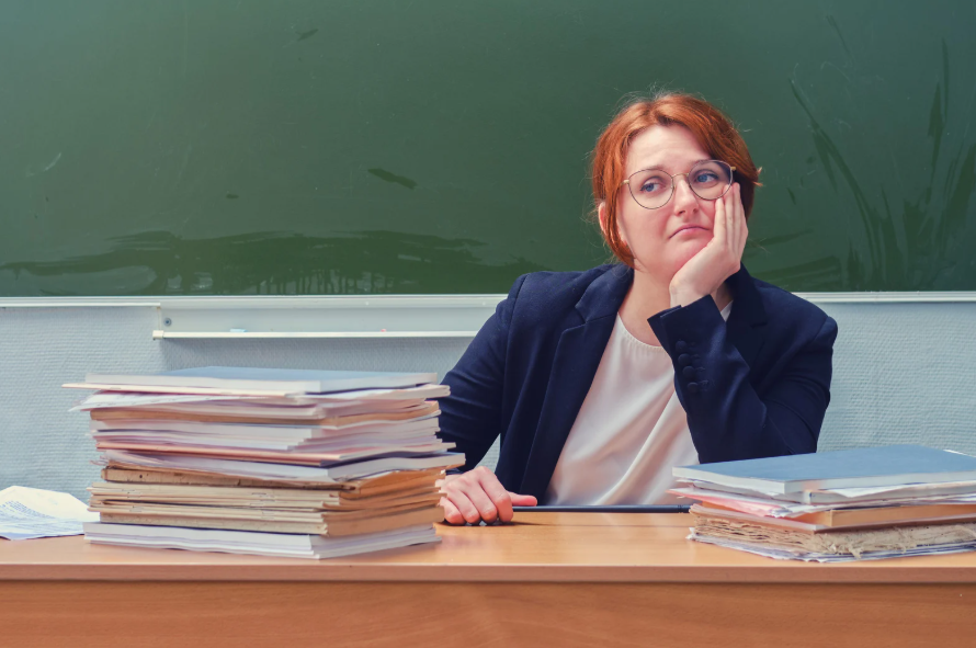 teacher experiencing emotional labor in teaching while sitting tired at a classroom desk