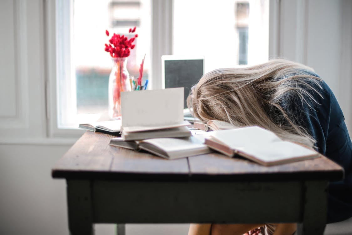 student experiencing mid-semester burnout while overwhelmed by schoolwork at desk